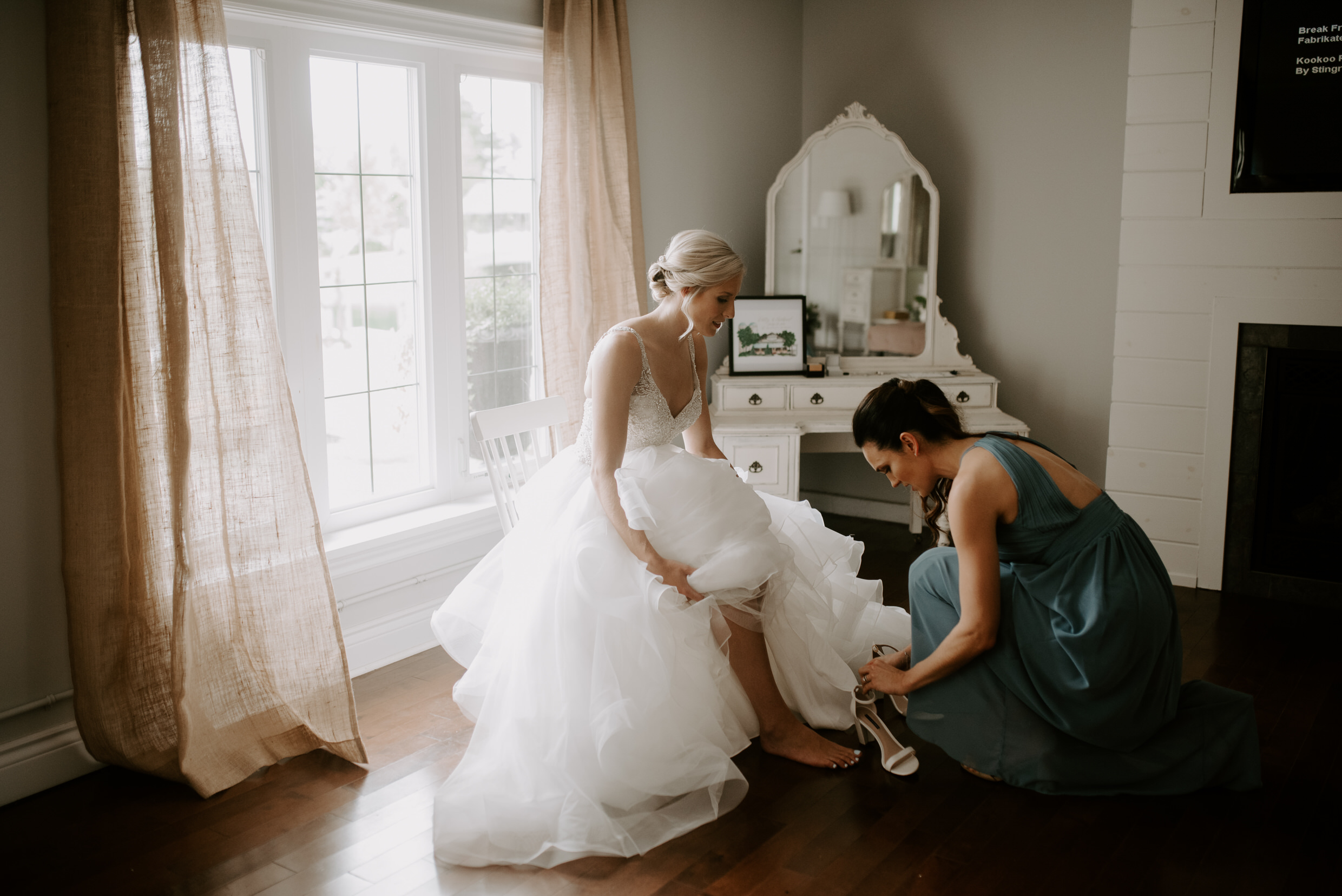 Belcroft Estates Wedding - bridesmaid helping bride with shoes